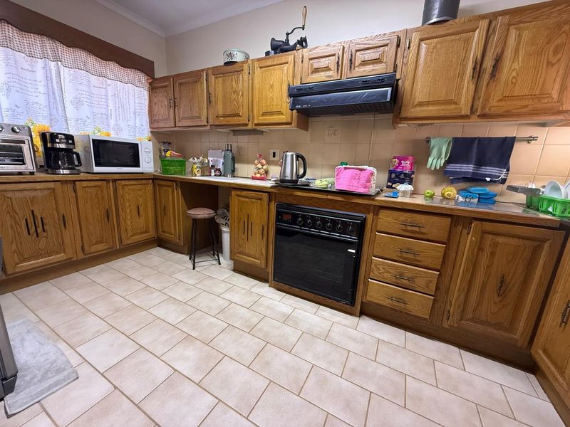 A functional kitchen featuring traditional oak cabinetry, tiled flooring, and a built-in oven with an extractor fan.