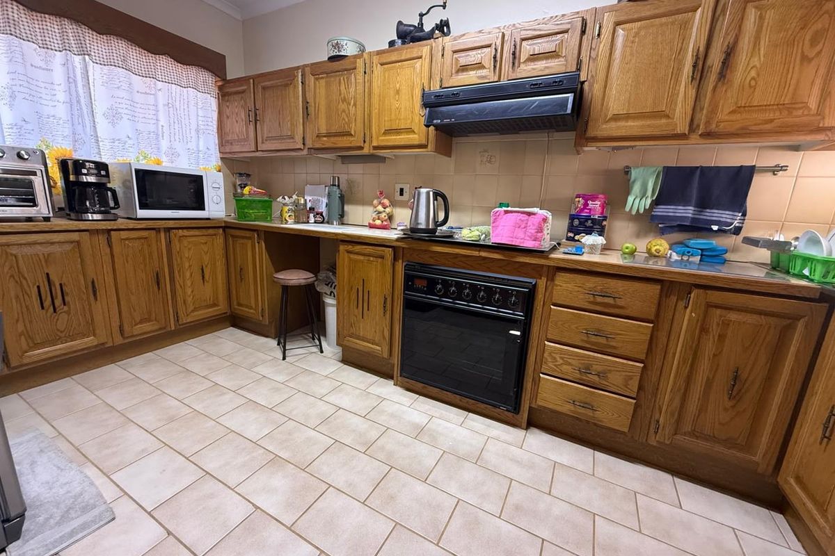 A functional kitchen featuring traditional oak cabinetry, tiled flooring, and a built-in oven with an extractor fan.