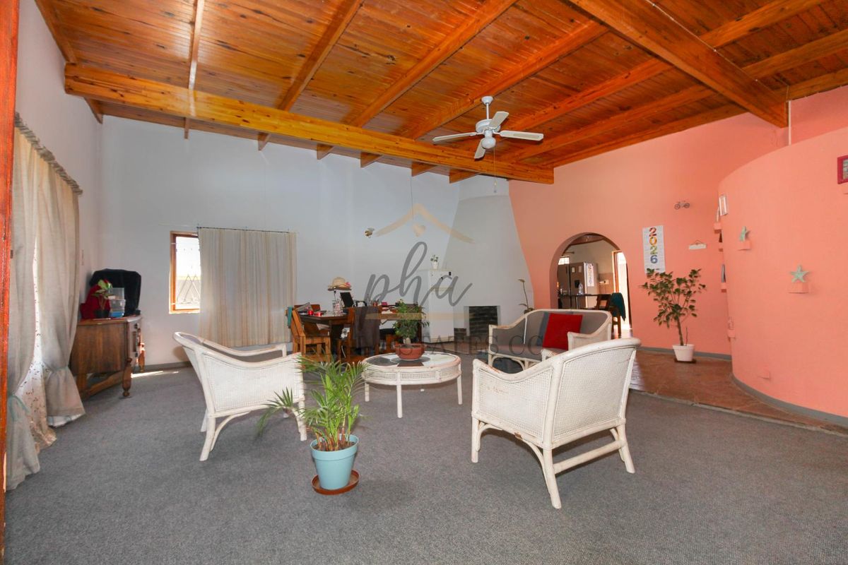 Spacious living area featuring exposed timber beam ceilings, a ceiling fan, and a built-in fireplace, offering a warm and rustic atmosphere.