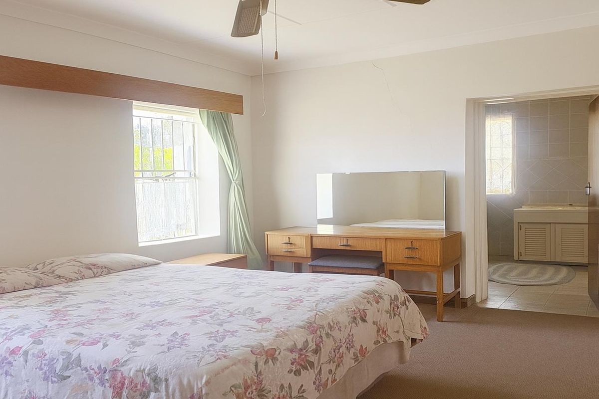 A bedroom featuring carpeted flooring, a ceiling fan, and an adjoining en-suite bathroom with tiled finishes.