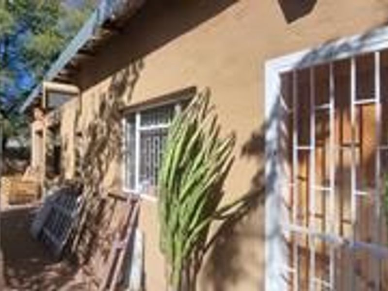 A view of the rear exterior of the house featuring a brick facade, security gate, and window security bars.