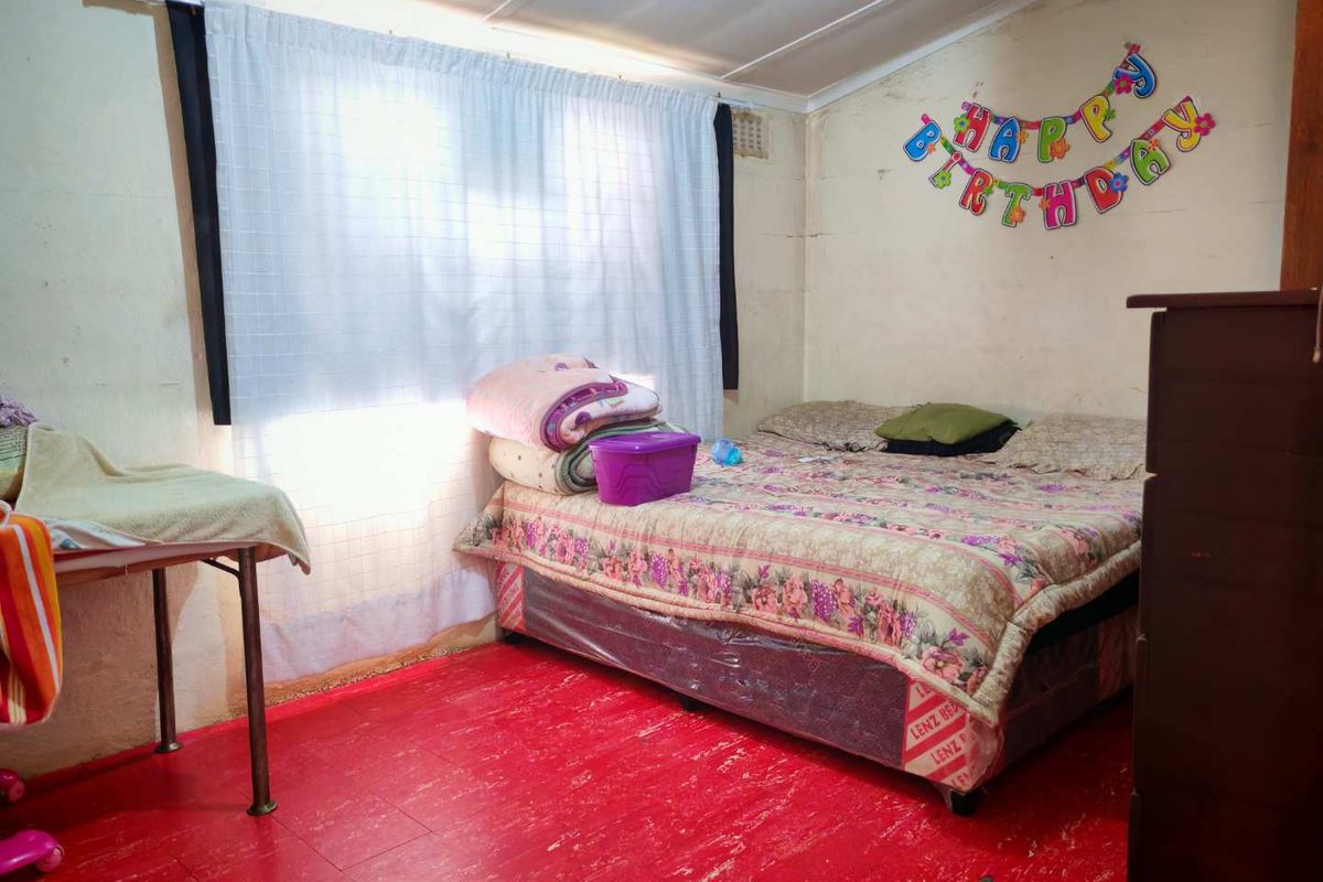 A bedroom featuring painted flooring and a window with curtain fixtures.