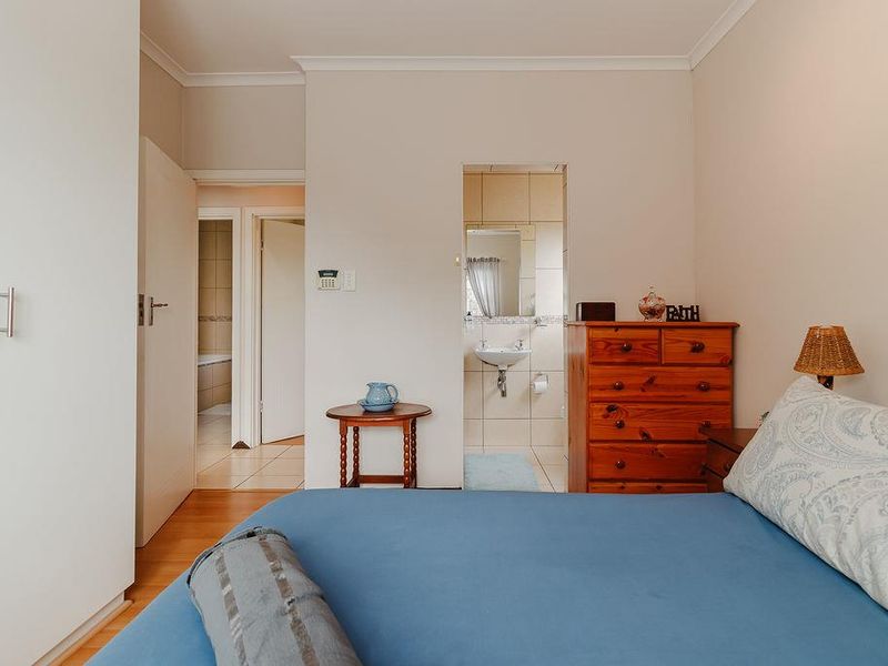 A bedroom featuring laminate flooring, built-in wardrobes, and direct access to an en-suite bathroom.