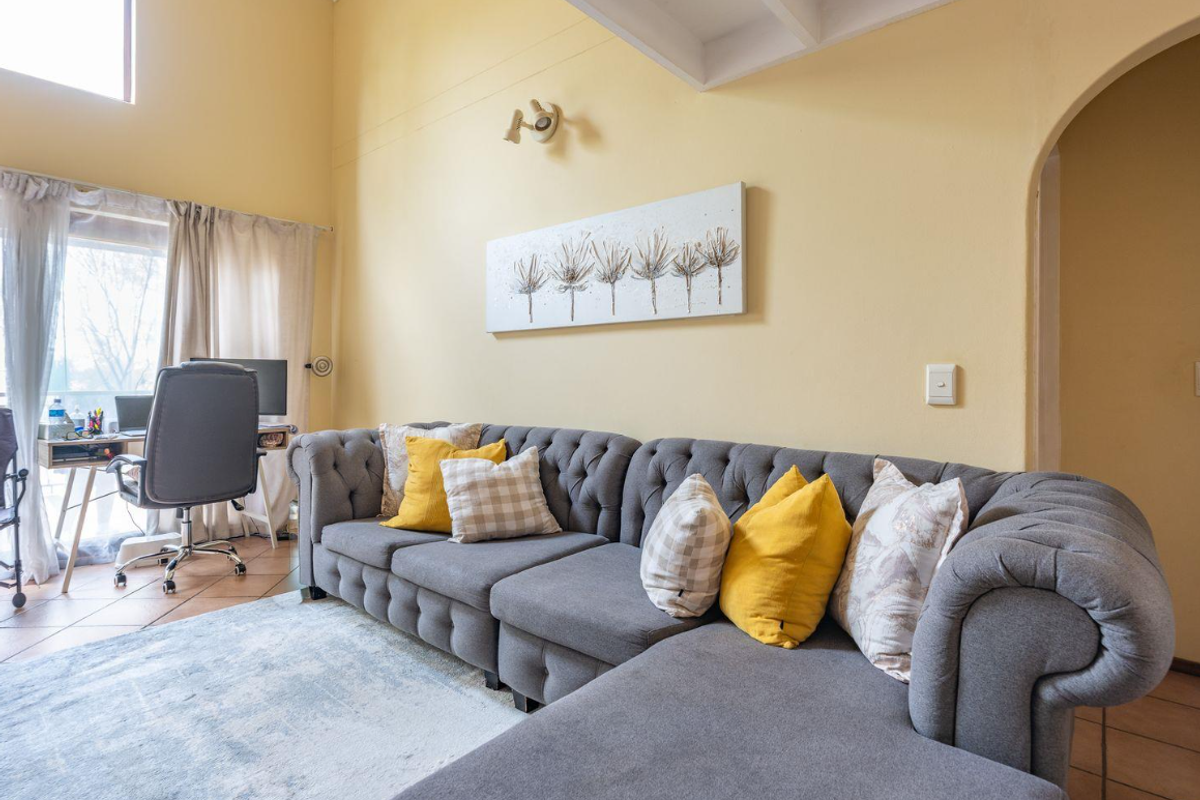 A living room featuring a vaulted ceiling, tiled flooring, and an arched doorway, providing a bright and spacious atmosphere.