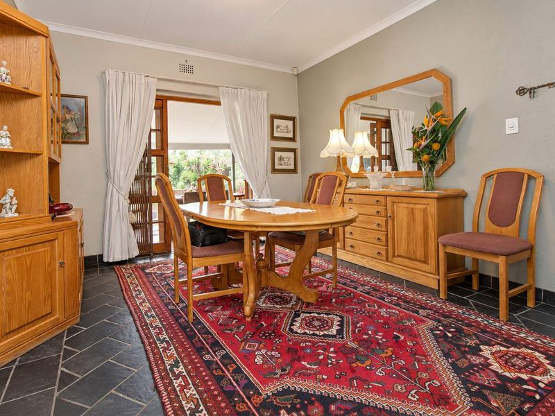 A traditional dining room featuring slate tile flooring and a timber-framed glass door providing access to the outdoor area.