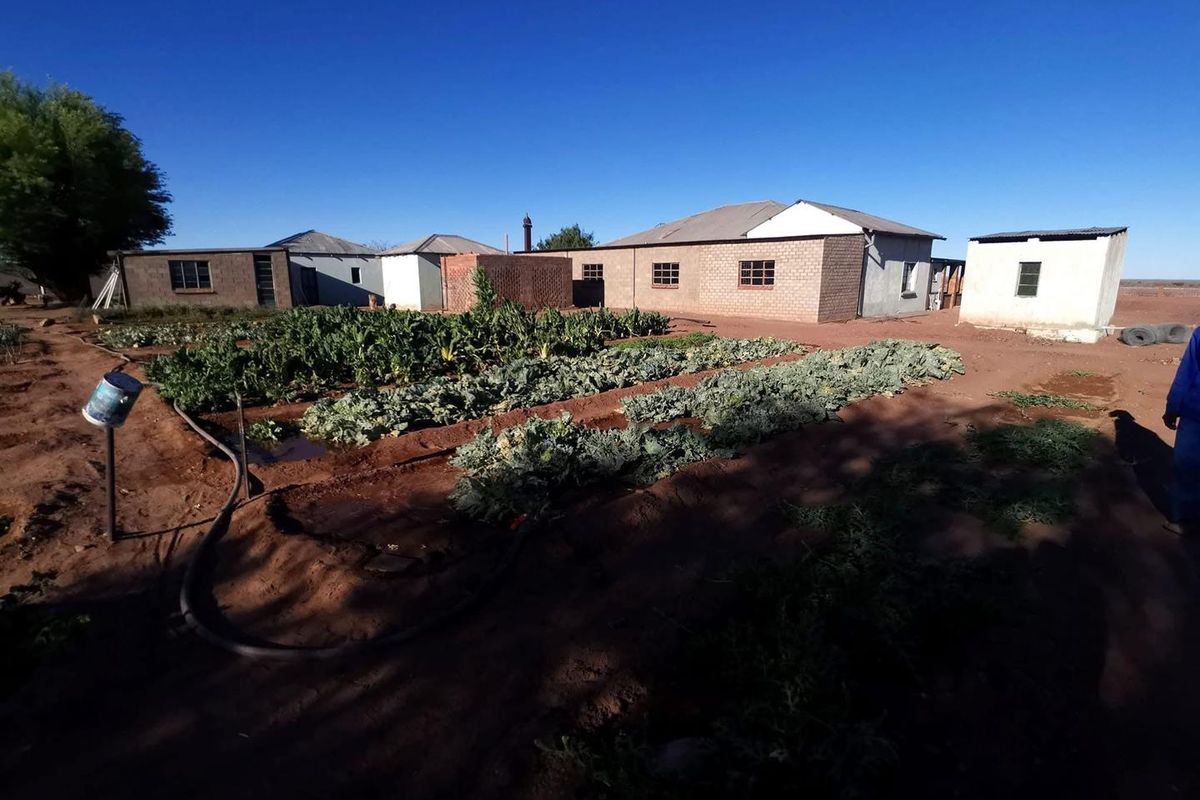 A view of the farm property featuring multiple outbuildings and a cultivated vegetable garden area on the grounds.