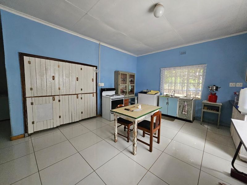 A functional kitchen featuring tiled flooring, built-in cabinetry, and a freestanding stove, offering a dated aesthetic with potential for modernization.