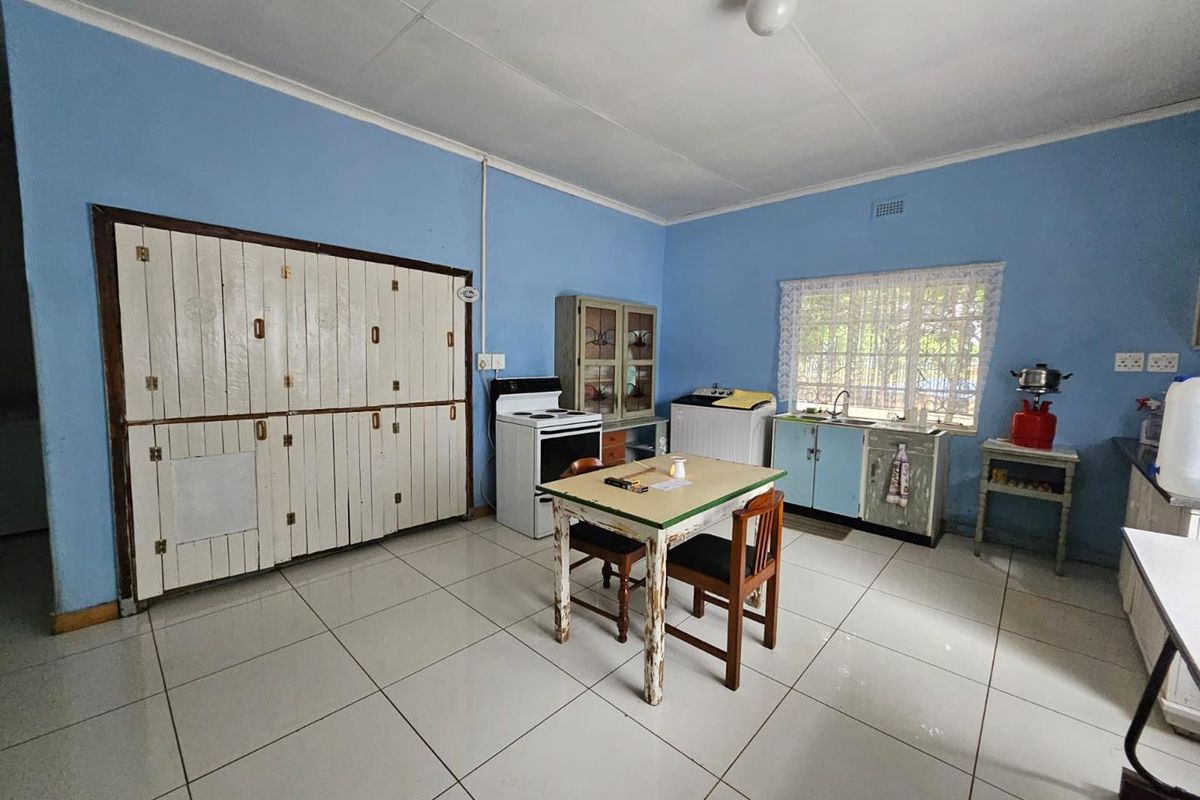 A functional kitchen featuring tiled flooring, built-in cabinetry, and a freestanding stove, offering a dated aesthetic with potential for modernization.
