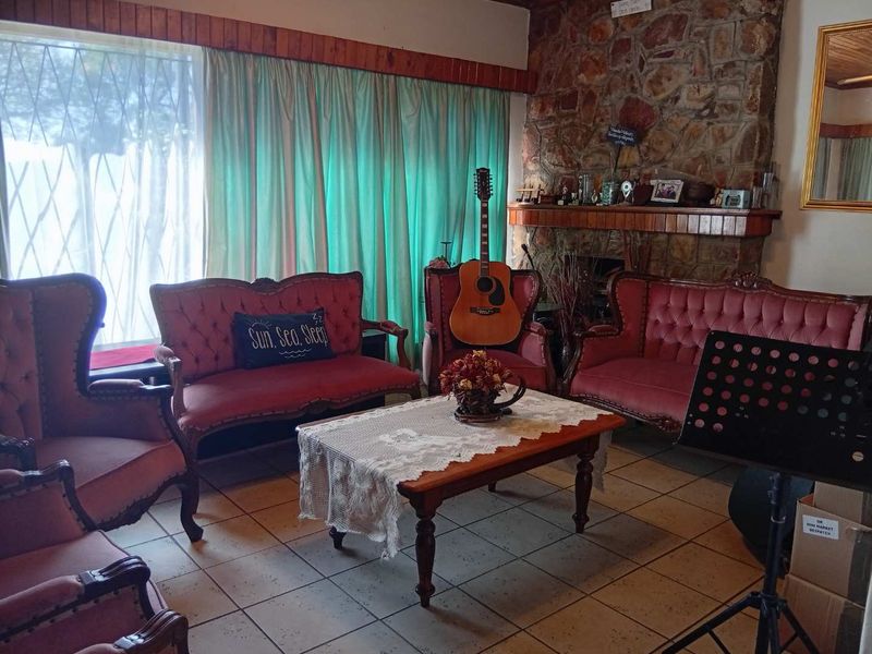 A living room featuring a prominent stone fireplace with a wooden mantelpiece and ceramic tiled flooring.