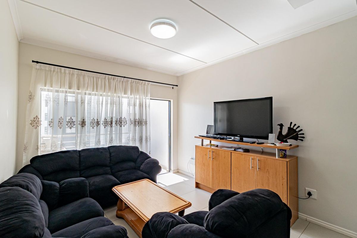 A functional living room featuring tiled flooring, a ceiling light fixture, and a sliding glass door providing access to the exterior.