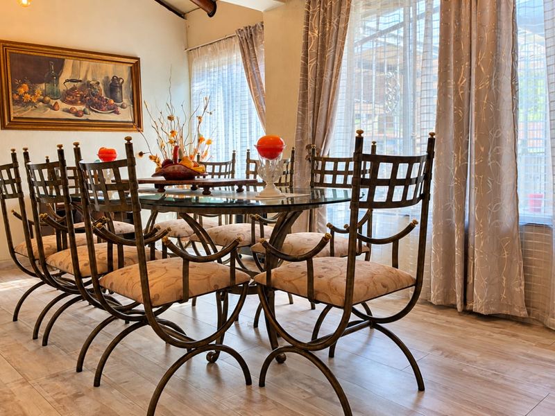 A bright dining room featuring wood-look tile flooring and large windows with natural light, providing a comfortable space for family meals.