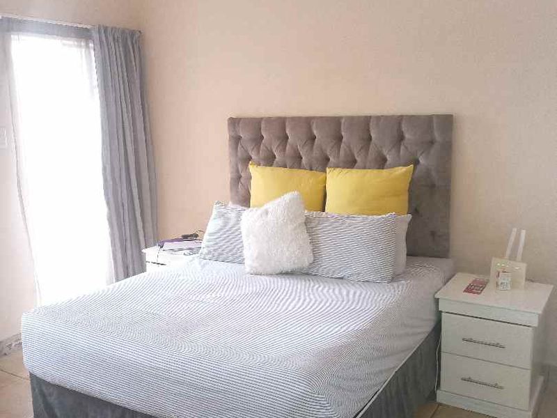 A bedroom featuring tiled flooring and a sliding glass door providing natural light.