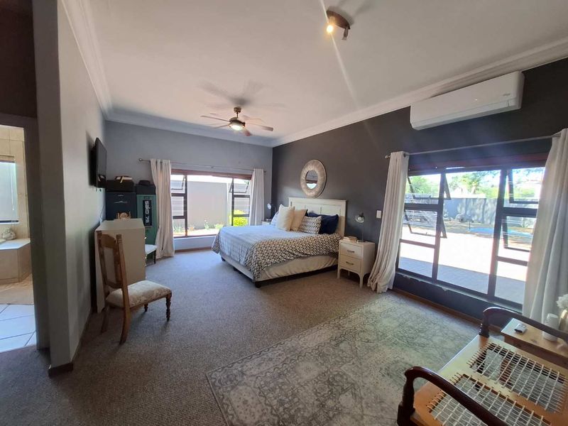 Spacious bedroom featuring carpeted flooring, a ceiling fan, split-system air conditioning, and large windows with direct access to the outdoor area.