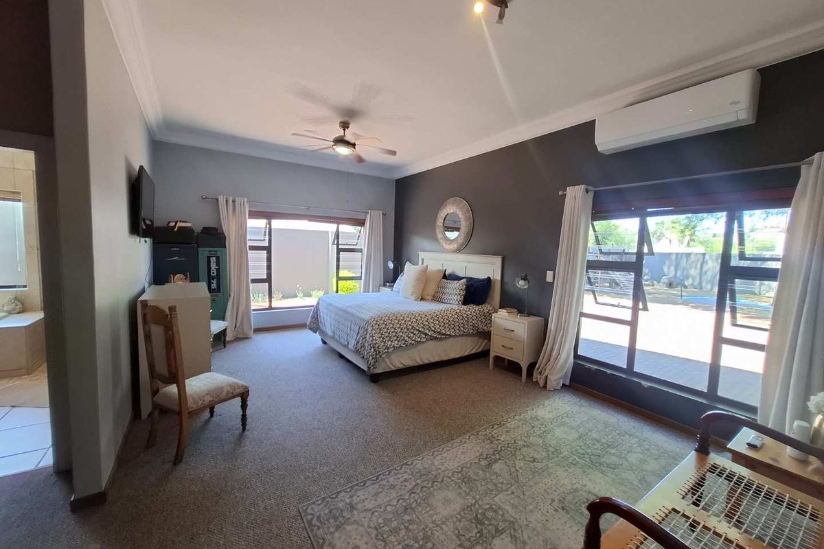 Spacious bedroom featuring carpeted flooring, a ceiling fan, split-system air conditioning, and large windows with direct access to the outdoor area.