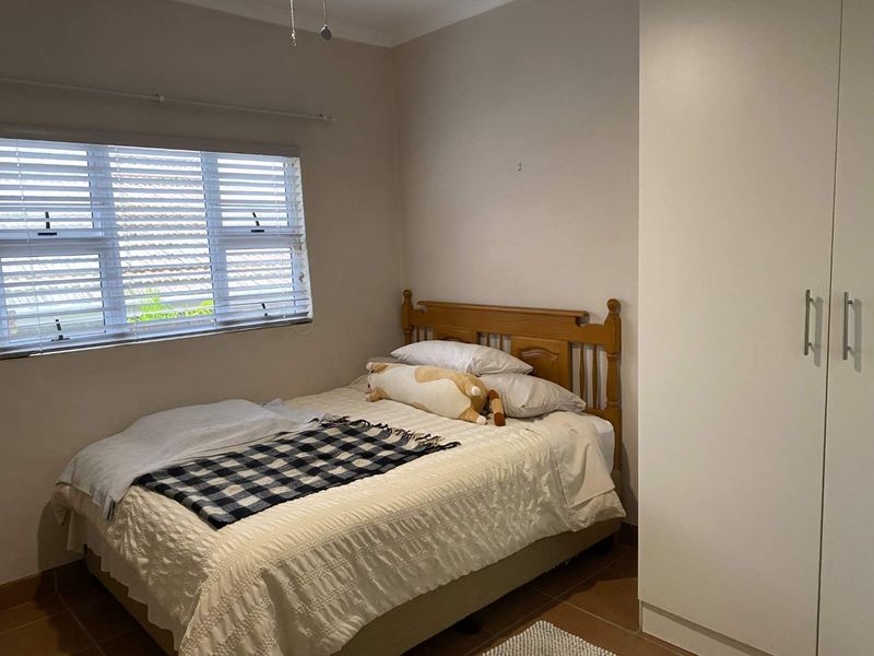 A functional bedroom featuring tiled flooring, a built-in wardrobe, and venetian blinds, offering a neutral base for personalization.