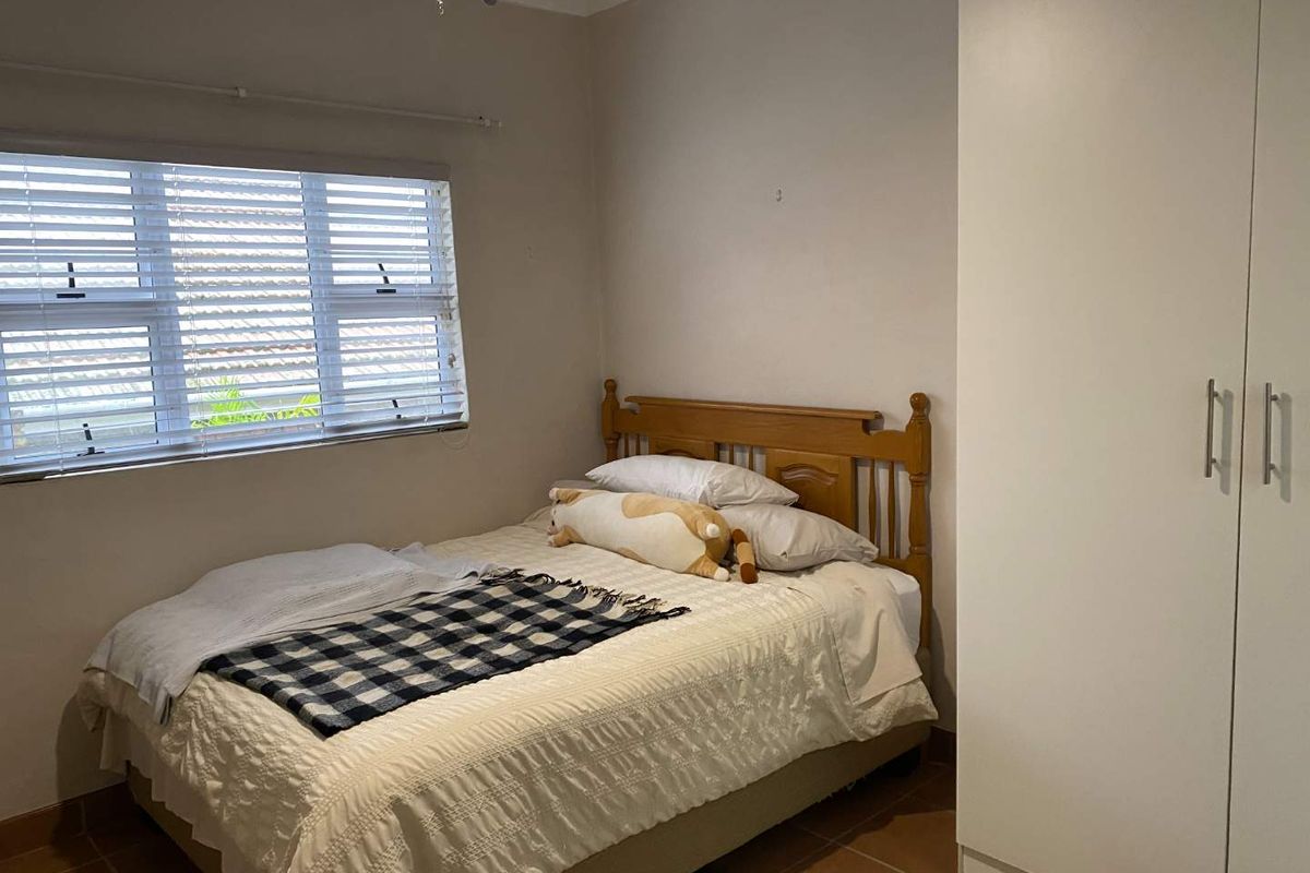 A functional bedroom featuring tiled flooring, a built-in wardrobe, and venetian blinds, offering a neutral base for personalization.