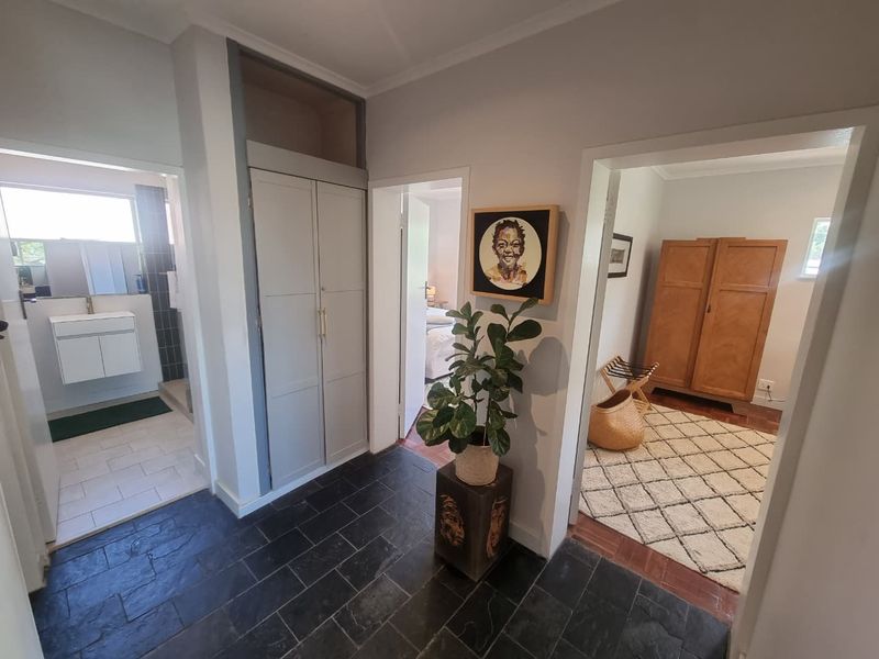 A well-maintained hallway featuring dark slate flooring, a built-in storage cupboard, and direct access to adjacent rooms.