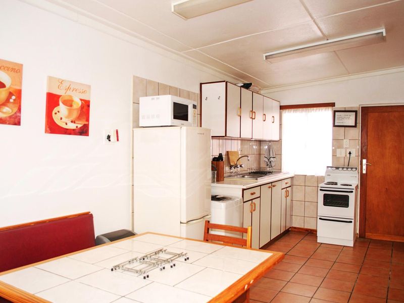 A functional kitchen featuring tiled flooring, built-in cabinetry, a tiled backsplash, and a freestanding stove, offering a practical layout for daily meal preparation.