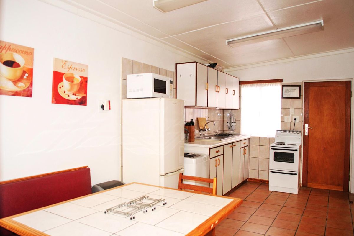 A functional kitchen featuring tiled flooring, built-in cabinetry, a tiled backsplash, and a freestanding stove, offering a practical layout for daily meal preparation.