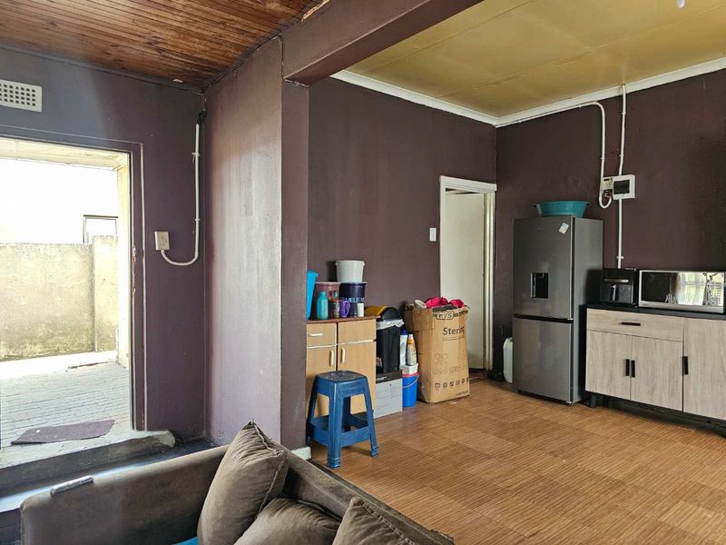 Open plan living area featuring laminate flooring, timber ceiling, and built-in cabinetry with exposed electrical conduit.