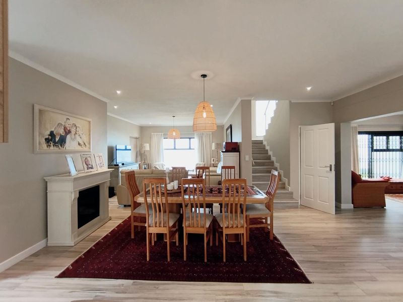 Spacious open-plan living and dining area featuring a fireplace, staircase, and modern laminate flooring with neutral wall finishes.