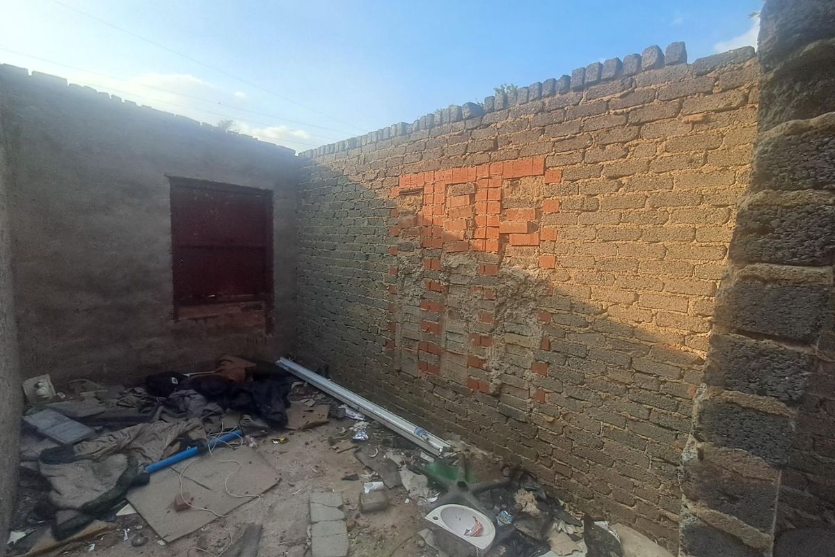An unfinished, derelict interior space featuring exposed brick walls and significant debris, requiring extensive renovation or structural repair.