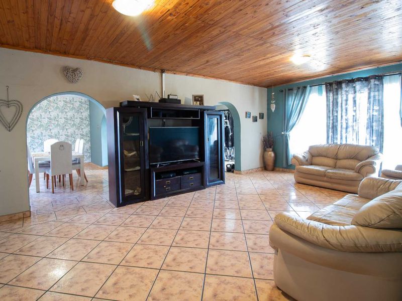 Spacious open-plan living and dining area featuring tiled flooring, a timber-clad ceiling, and arched architectural transitions between rooms.
