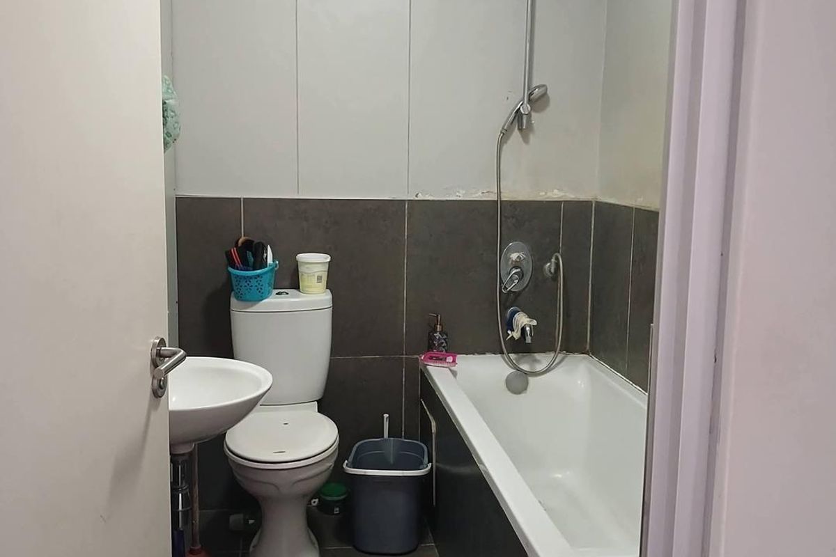Compact bathroom featuring a pedestal basin, toilet, and a bathtub with a handheld shower mixer, finished with dark floor and wall tiles.
