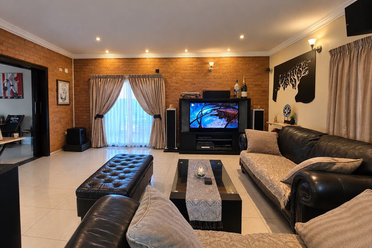 Spacious living room featuring an exposed brick feature wall, tiled flooring, and recessed downlighting, creating a warm and inviting atmosphere.