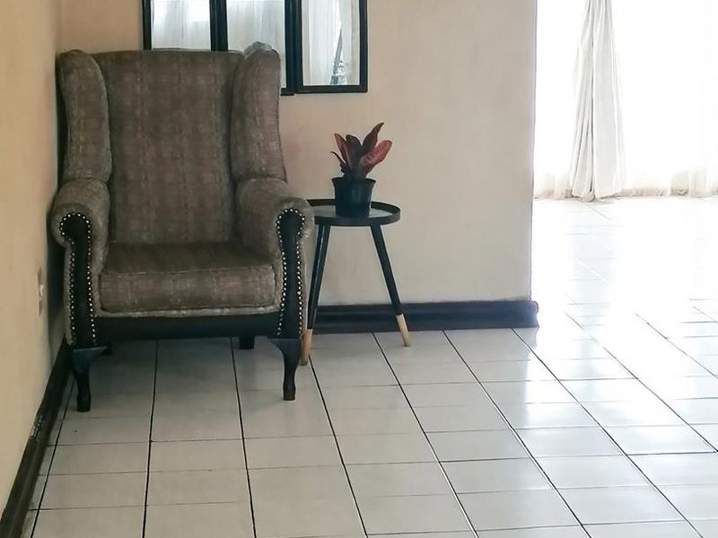 A living area featuring neutral ceramic floor tiles and simple wall finishes, providing a clean and functional space.