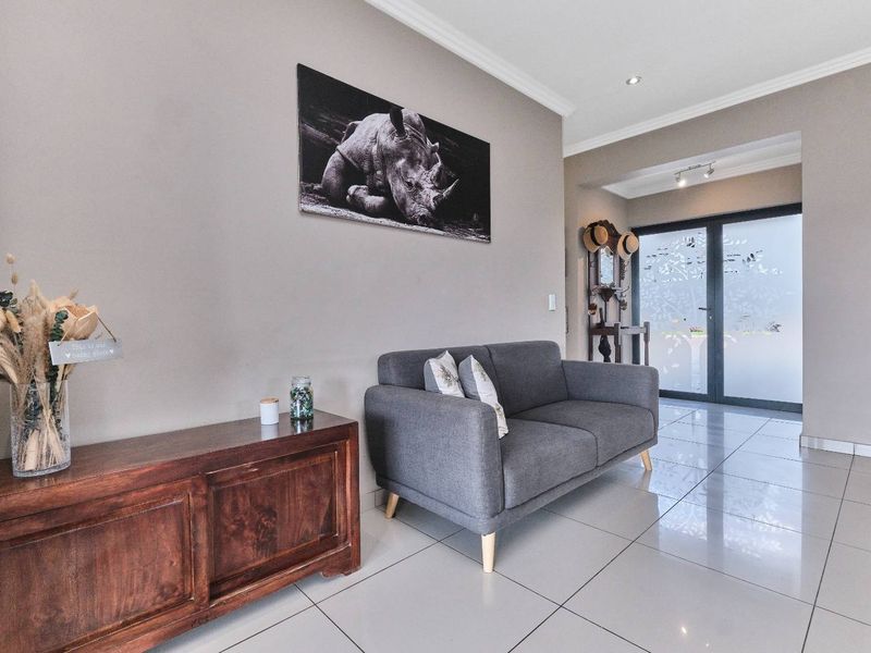 A bright and modern entrance hall featuring polished tiled flooring, neutral wall tones, and a stylish frosted glass front door.