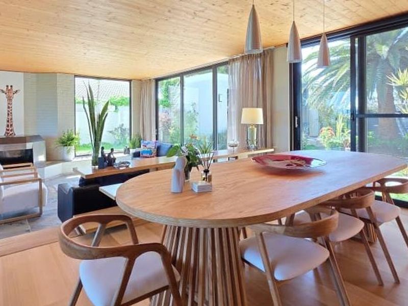 Spacious open-plan living and dining area featuring a timber ceiling, hardwood flooring, a fireplace, and large sliding glass doors opening to the garden.