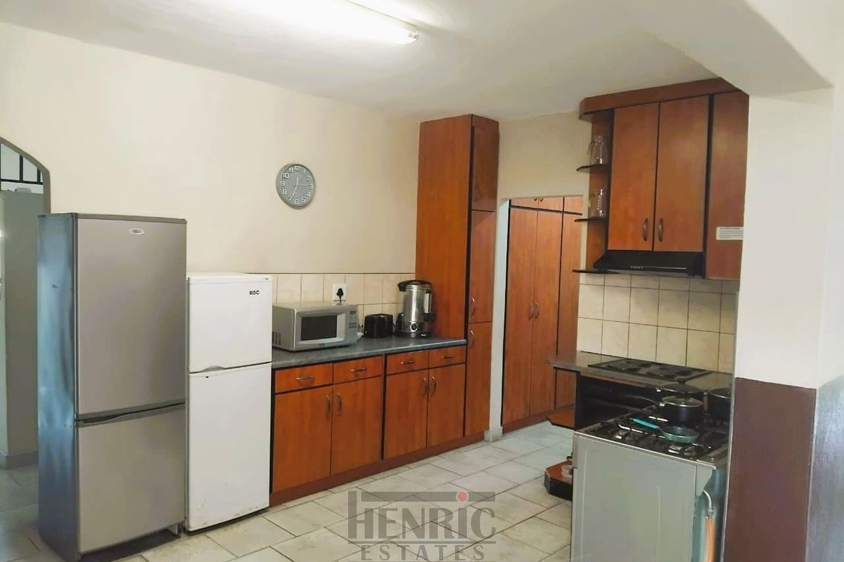 A functional kitchen featuring wooden cabinetry, tiled backsplash, and built-in stove with extractor fan, offering a practical layout for daily meal preparation.