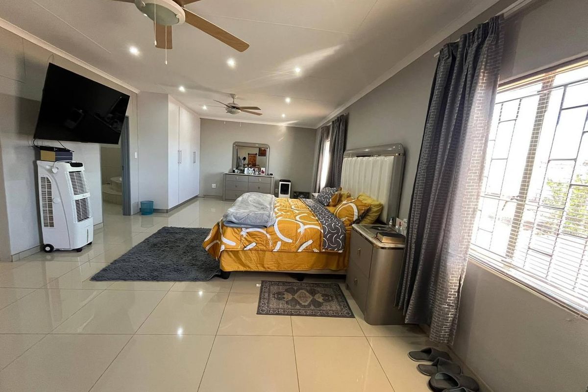 Spacious bedroom featuring tiled flooring, recessed lighting, ceiling fans, and built-in cupboards with an en-suite bathroom access.
