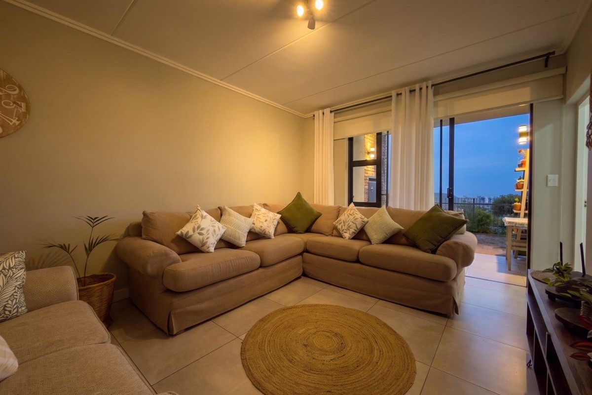 A comfortable living room featuring large format floor tiles and a sliding glass door providing access to an outdoor balcony area.