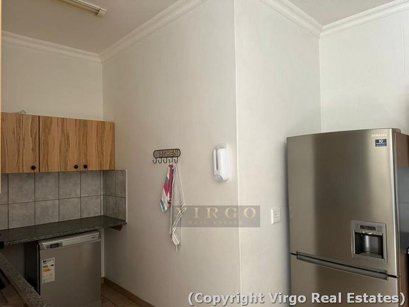 A functional kitchen area featuring laminate cabinetry, granite countertops, and tiled splashbacks, providing a practical workspace for daily culinary activities.