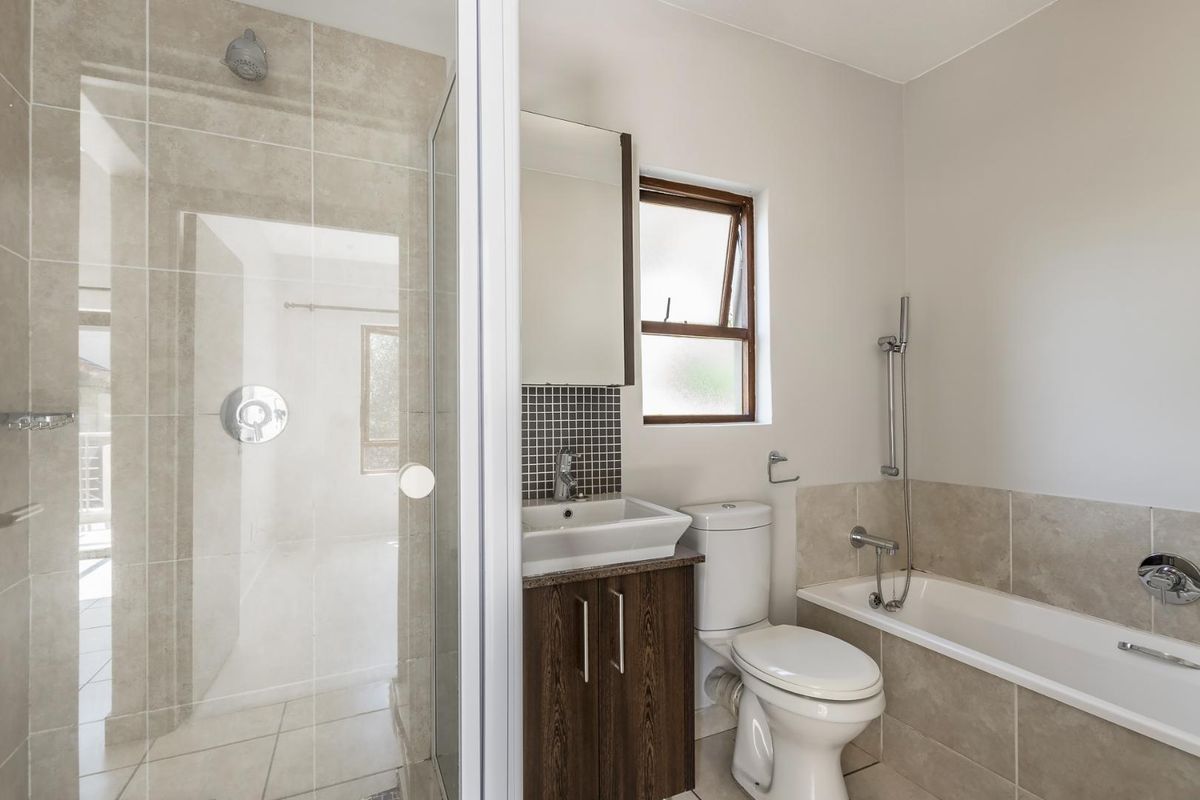 Modern bathroom featuring a glass-enclosed shower, a separate bathtub with handheld showerhead, a vanity basin, and a toilet.