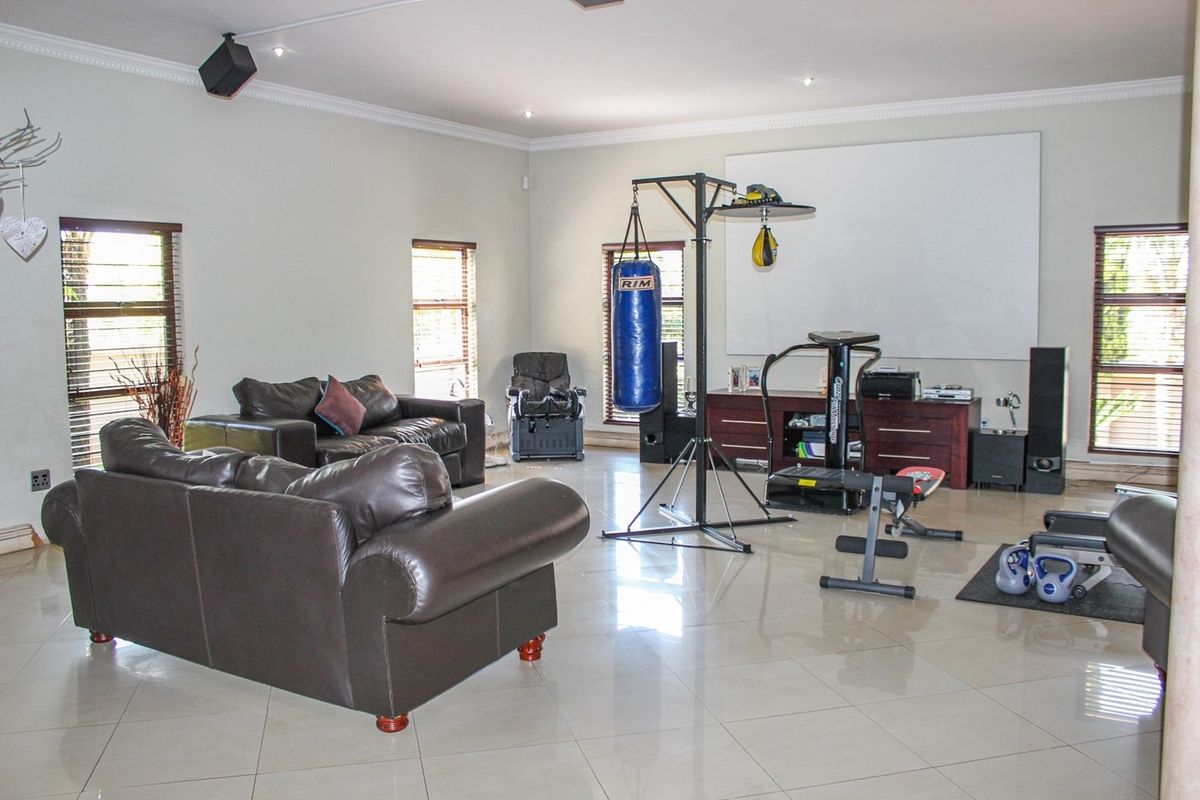 Spacious living area featuring large format floor tiles, recessed downlighting, and multiple windows with fitted blinds.