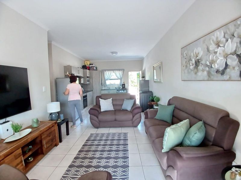 Open-plan living area featuring tiled floors and a functional kitchen with built-in cabinetry, oven, and extractor fan.