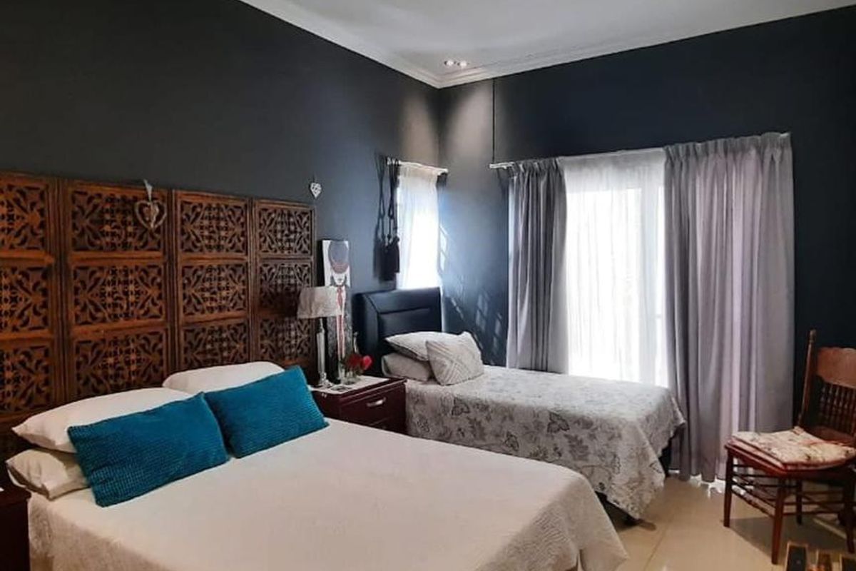 A spacious bedroom featuring tiled flooring, recessed ceiling lighting, and large windows with curtains, providing ample natural light.