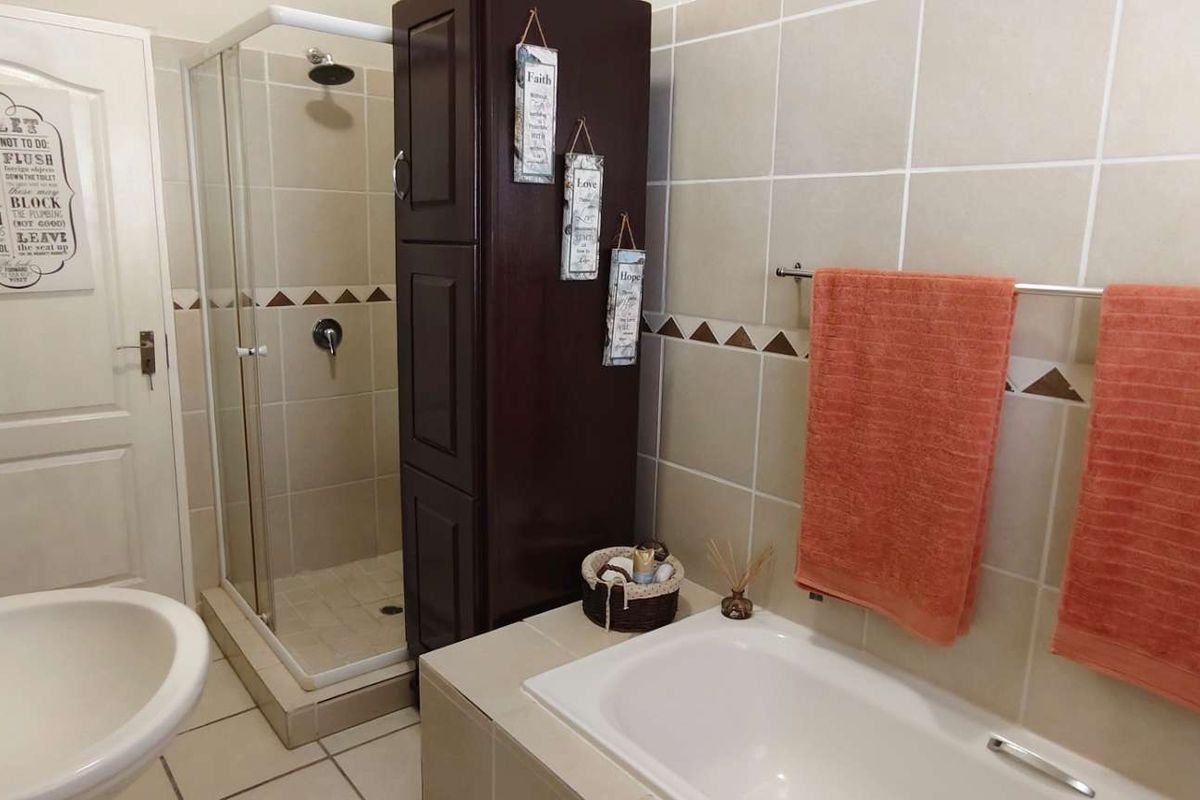 A functional bathroom featuring a built-in bathtub, a separate glass-enclosed shower, tiled walls, and a pedestal sink.