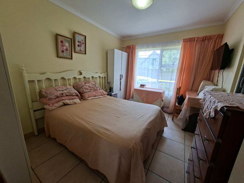 A functional bedroom featuring tiled flooring, coving, and a large window allowing natural light into the space.