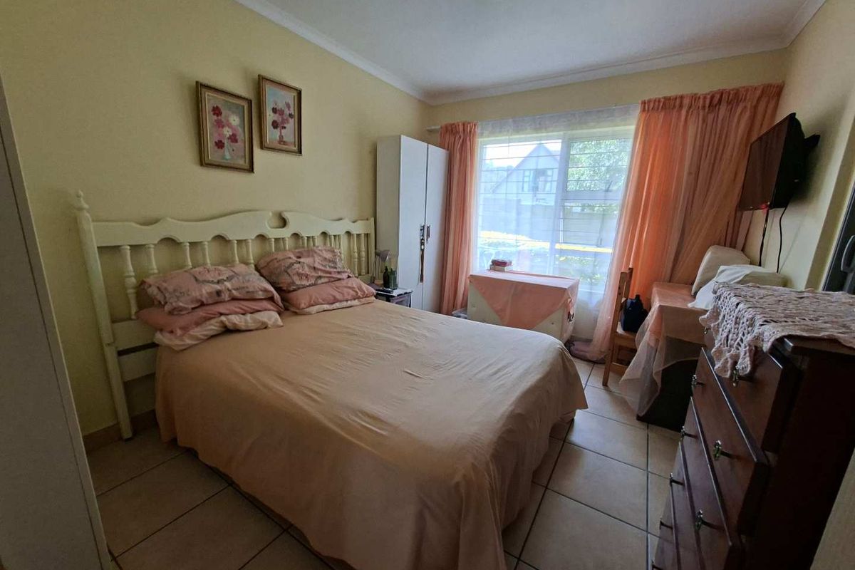 A functional bedroom featuring tiled flooring, coving, and a large window allowing natural light into the space.