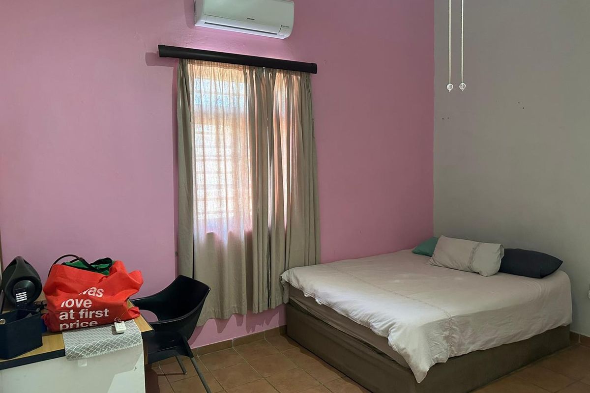 A bedroom featuring tiled flooring, a wall-mounted air conditioning unit, and a window with curtain fixtures.
