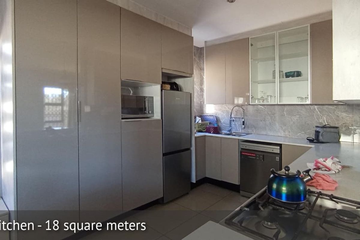 Modern kitchen featuring high-gloss cabinetry, stone-look backsplash, integrated microwave space, stainless steel sink, and a gas hob.
