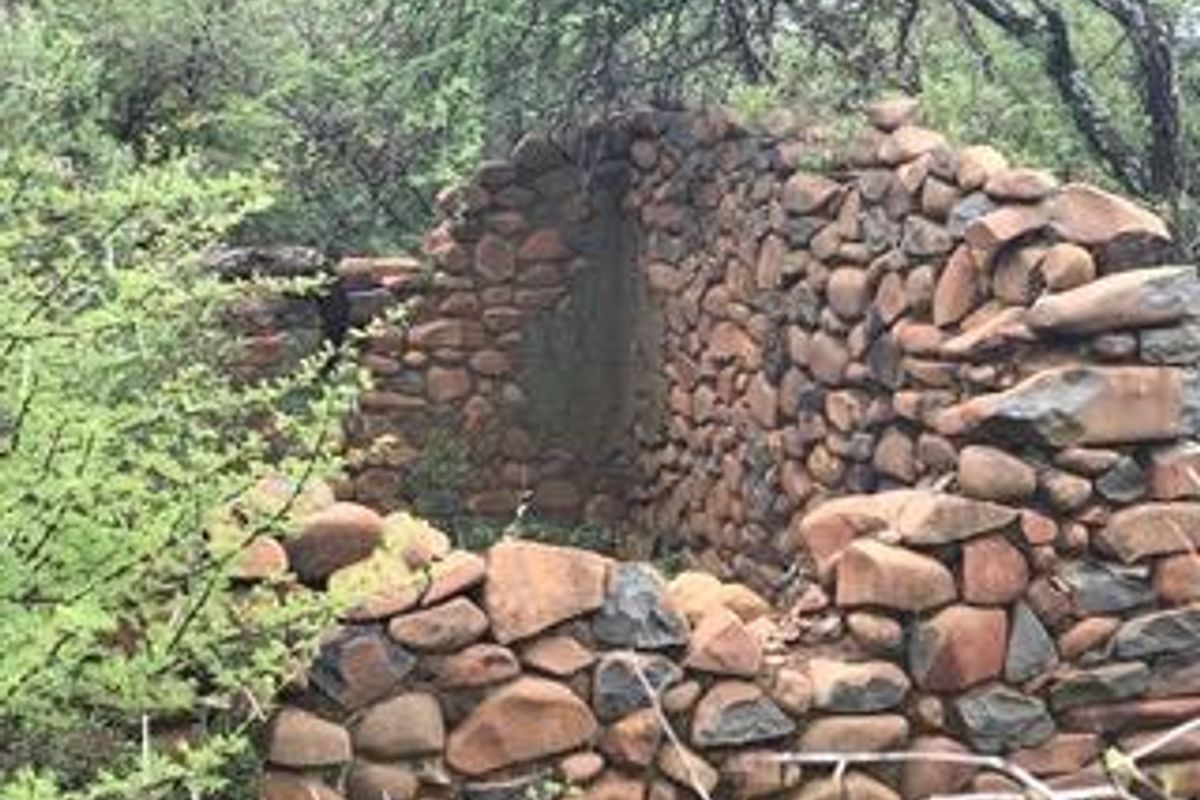A view of a dilapidated, partially collapsed historic stone wall structure situated on the vacant residential land.