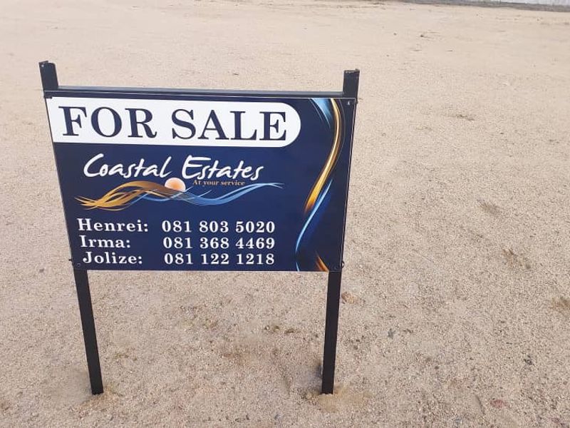 A vacant residential plot featuring a real estate for sale sign.