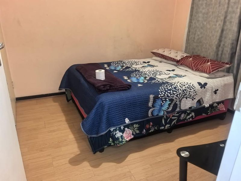 A bedroom featuring laminate flooring and plain walls, requiring cosmetic updates to improve the overall aesthetic and condition of the space.