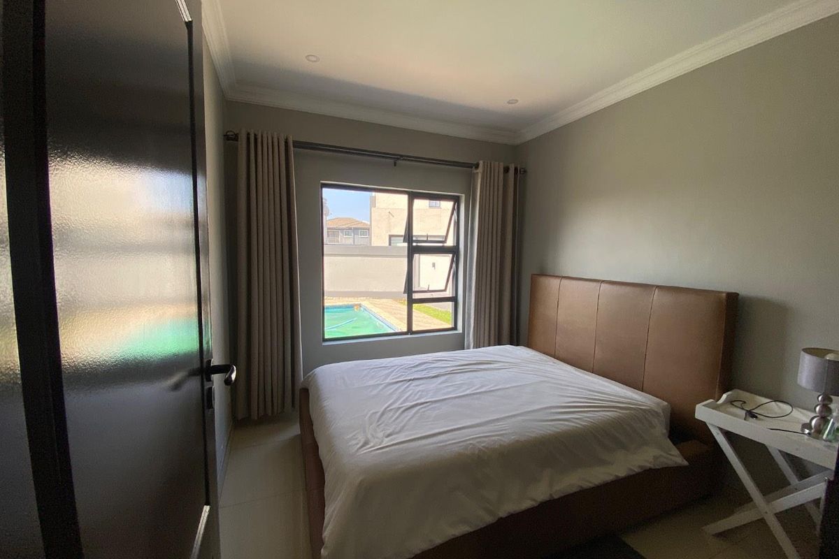 A well-maintained bedroom featuring neutral wall tones, tiled flooring, and a window view overlooking the outdoor pool area.