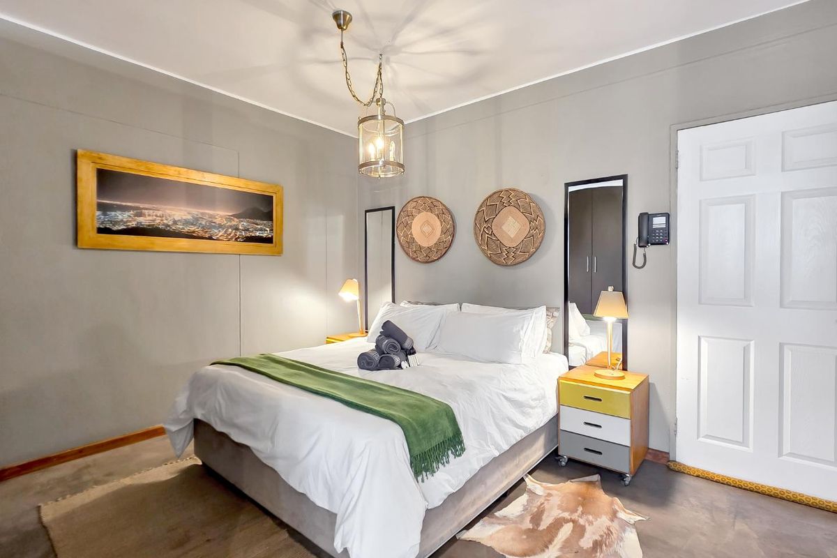 A well-lit bedroom featuring neutral wall tones, a central pendant light fixture, and a functional wall-mounted intercom system.
